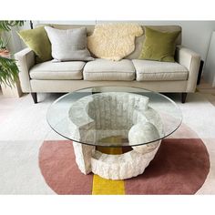 a glass table sitting on top of a rug next to a couch