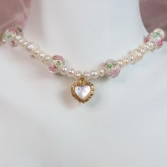 The Pink Rose Pearl Necklace features a stainless steel heart pendant surrounded by freshwater pearls and rose beads. This adjustable pearl choker, ranging from 14"-17", showcases a coquette aesthetic, perfect for adding a bit of vintage to any outfit. Hypoallergenic and waterproof, it's designed for both style and comfort.   * Stainless Steel * Skin-friendly * Waterproof * Adjustable Chain 14"-17" * Lobster Claw Clasp * Made in Texas Cheap Pink Necklace With Pearl Charm, Rose Gold Beaded Pearl Necklaces, Pink Pearl Necklace With Heart Beads Gift, Charming Pink Necklace For Wedding, Feminine Pearl Beaded Necklaces, Beaded Pearl Necklace For Valentine's Day, Dainty Pink Pearl Beaded Necklaces, Pink Heart-shaped Pearl Necklace, Heart-shaped Pink Pearl Necklace