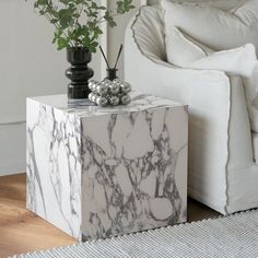 a white marble side table with two vases on top