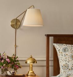 a bedroom with a bed, lamp and flowers on the nightstand next to the bed