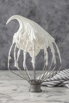 a whisk with white icing on top of it sitting on a counter