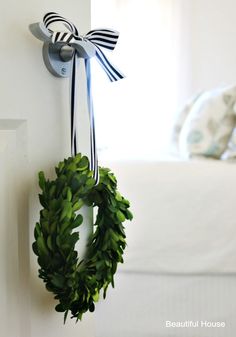 a green wreath hanging on the wall next to a white door with a black and white bow