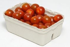 a white container filled with lots of red tomatoes