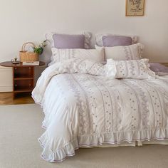 a bed with white and purple comforters in a bedroom