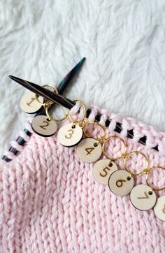 a pair of scissors is laying next to a knitted sweater with personalized keychains on it