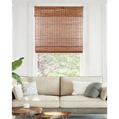 a living room filled with furniture and a window covered in bamboo blind shades on the windowsill