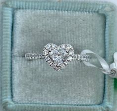 a heart shaped diamond ring in a velvet box with a ribbon around the band and two diamonds on each side