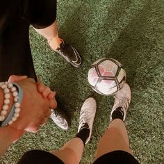 two people holding hands and standing next to a soccer ball