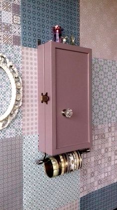 a pink cabinet mounted to the side of a wall next to a mirror and camera