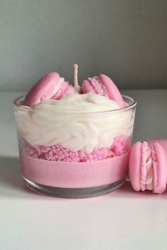 a glass bowl filled with pink and white frosted cookies next to a cupcake