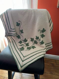 a white crocheted blanket sitting on top of a chair next to a window