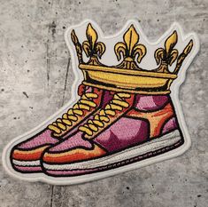 a pair of sneakers with a crown on top of them, sitting on the ground