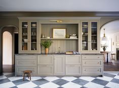 a kitchen with checkered flooring and built in cabinets on the wall, along with a potted plant