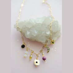 The Dainty Flower Charm Necklace is a multi-color, single strand charm necklace that is sure to be a happy addition to your jewelry collection. This necklace features assorted Czech glass, gemstones, glass beads, and Mother of Pearl. The seven charms rest towards the bottom of the design and feature an assortment of shapes and colors like a crescent moon, a gem-set sun to flowers and more. This necklace also features gold plated over brass chain and a lobster clasp. The contrast of color against Flower Charm Necklace, Flower Charm, Brass Chain, Czech Glass, Mother Of Pearl, Charm Necklace, Multi Color, Jewelry Collection, Glass Beads