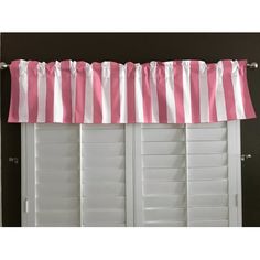 the pink and white striped valance is hanging over the window