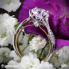 a diamond ring sitting on top of white flowers next to purple and white carnations