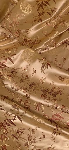 a close up view of the fabric with flowers and leaves on it, in gold