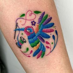 a colorful tattoo on the leg of a woman with scissors and flowers in it's center