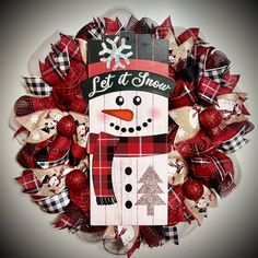 a christmas wreath with a snowman on the front and red plaid bow around it