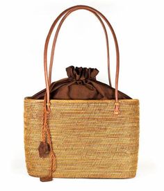 The Lisi Lerch Bali Bag collection is all handwoven by local artisans of the Tenganan region of Bali. Each weaver creates these works of art by using ata grass, a vine indigenous to the foothills of volcanoes on their beautiful Indonesian Island. The bags are then smoked in a coconut and honey fire to achieve their luscious golden hue. Our amazing team in Baltimore then adorns each bag so that they are as unique in character as the women who carry them. Whether you are strolling down the cobbled streets of Nantucket, sipping rosé in Charleston, or sunbathing poolside at your favorite resort, these one of a kind bags will surely turn heads! Size 7Wx5Hx4D 48 inch strap Materials Hand Woven Ata Grass Genuine Leather Strap Lining: Hand Loomed Cinnamon Cotton Features Drawstring Closure Crossbo Brown Natural Fiber Beach Bag With Open Weave, Brown Open Weave Beach Bag In Natural Fiber, Brown Open Weave Beach Bag Made Of Natural Fiber, Brown Woven Rattan Bag, Natural Fiber Bucket Bag With Bamboo Handle, Brown Basket Bag With Open Weave, Casual Brown Palm Leaf Bag, Brown Open Weave Basket Beach Bag, Brown Basket Beach Bag With Open Weave