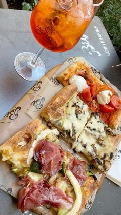 two slices of pizza sitting on top of a table next to a glass of wine