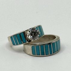 two wedding rings with blue and white stripes on each band, one has a diamond in the center