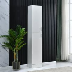 a tall white cabinet next to a potted plant