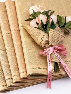 a bouquet of flowers sitting on top of an old newspaper with ribbon tied around it