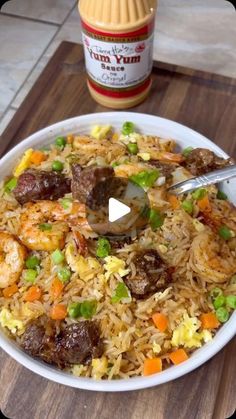 a bowl filled with rice, meat and veggies next to a jar of mustard