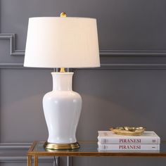 a white lamp sitting on top of a table next to a book and a glass table