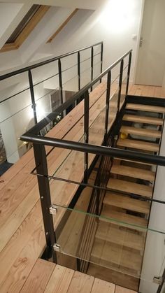 a stair case with glass railings and wood flooring in an empty loft space