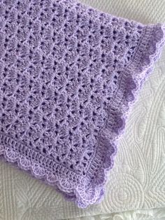 a purple crocheted blanket laying on top of a bed