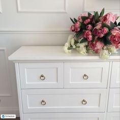 a white dresser with pink and white flowers on top