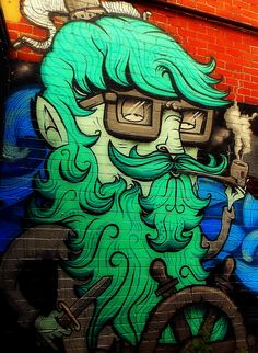 graffiti on the side of a building with a man's face and green hair