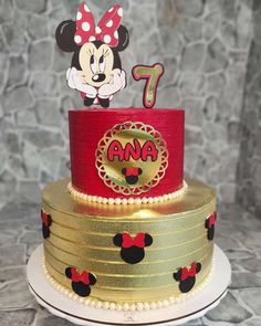 a three tiered cake with minnie mouse topper and number 1 on it's side