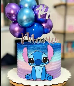 a blue and purple cake with an elephant on it's top is surrounded by balloons