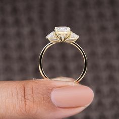 a woman's hand holding a yellow gold ring with two diamonds on the side