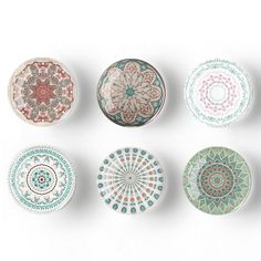 six different colored plates are arranged in a row on a white surface, each with an intricately designed design