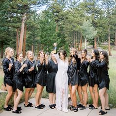 a group of women standing next to each other wearing black robes and holding champagne bottles