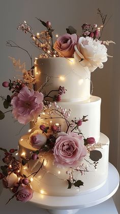 a three tiered wedding cake decorated with flowers and lights