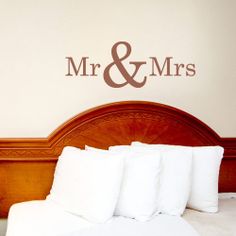 there is a bed with white pillows and a wall decal behind it that says mr & mrs