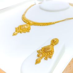 This 22k gold necklace set features a graceful design with elegant hanging tassels, perfect for adding sophistication to any look. Weighing 30.0 grams, the set is crafted from radiant yellow gold, with a 16-inch necklace that includes 1.75-inch adjustable links and a secure hook lock. The matching 1.75-inch earrings, fitted with screw-back posts, complete the ensemble with a refined touch. The tassel design adds movement and charm, making this set ideal for those who appreciate timeless elegance with a modern flair, perfect for special occasions PRODUCT DETAILS Gold Purity(karat): 22k Gold Weight(grams): 30.0 Item Finish: Yellow Gold Set Length: 16" Drop Length: 1.5" Adjustable Links: 1.75" Links Lock Style: Hook Lock Matching Earrings: Included Earring Length: 1.75" Earring Post: Screw Ba Traditional Yellow Gold Necklaces With Latkans, 22k Yellow Gold Kundan Necklace With Latkans, Elegant Gold Jewelry Sets With Latkans, Festive Formal Necklace With Latkans, Festive Gold Dangle Necklaces, Traditional Gold Dangle Necklace, Elegant 22k Gold Kundan Necklace With Latkans, Ceremonial Yellow Gold Necklaces With Latkans, Elegant Gold Temple Necklace With Latkans