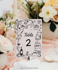 a table number is displayed on top of a table with flowers and candles in the background