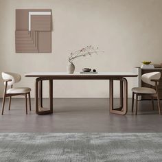 a dining table with two chairs and a vase on it in front of a beige wall