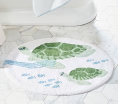 a bathroom rug with two green turtles on it next to a toilet in a bathroom