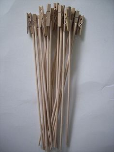 several wooden sticks with clothes pins attached to them on a white surface, lined up against each other