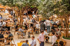 many people are sitting at tables and eating food in a restaurant with trees growing on the walls