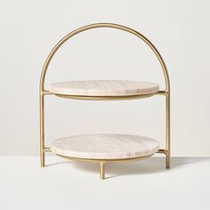 two tiered white marble display stand with gold metal frame and round shelves on each side