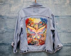 a jean jacket with an image of a woman's breast on it hanging up against a wall