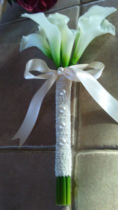 a boutonniere with white flowers and pearls on the end is tied to a tile floor